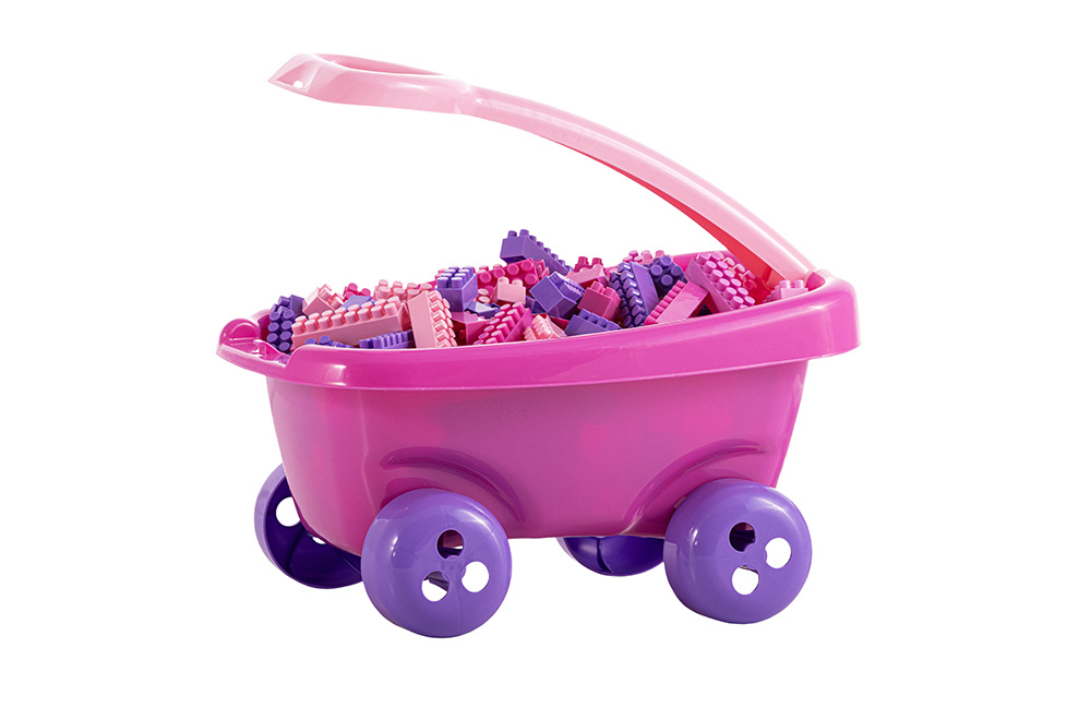 Różowy wózek na kółkach z jasnym uchwytem, wypełniony różowo-fioletowymi klockami konstrukcyjnymi.